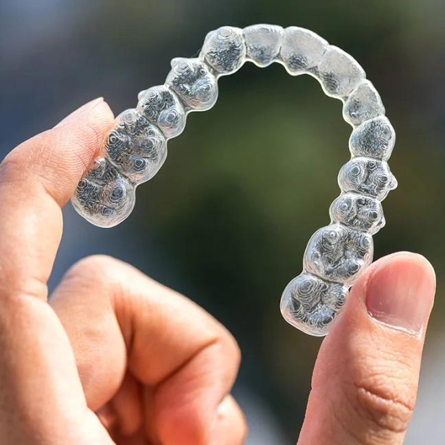 Clear Invisalign aligner held for orthodontic treatment